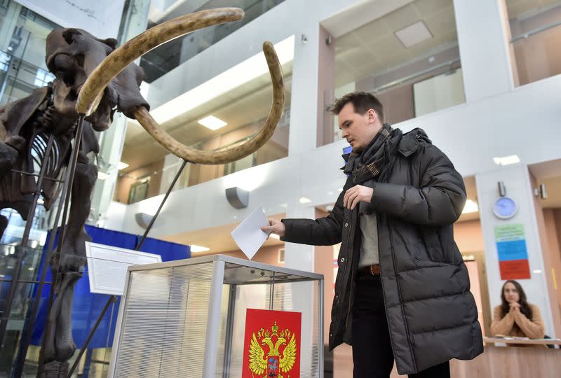 Un hombre deposita su voto cerca de un esqueleto de mamut en un colegio electoral situado en la Universidad Estatal de Novosibirsk, en el último día de las elecciones presidenciales en Novosibirsk, Rusia