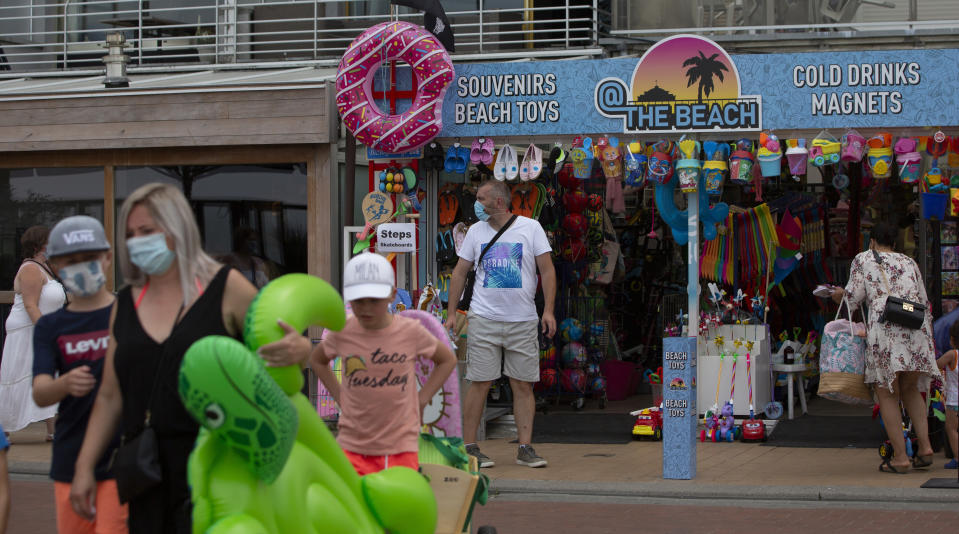 People shop on the promenade at the Belgian seaside resort of Blankenberge, Belgium, Tuesday, Aug. 11, 2020. A skirmish took place on the beach on Saturday, Aug. 8, 2020 which resulted in two coastal communities banning day trippers from the city. (AP Photo/Virginia Mayo)