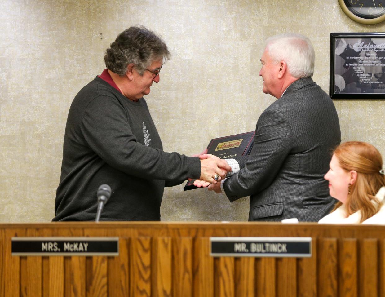 Lafayette School Corporation school board member David R. Moulton (District I) hands Stephen J. Bultinck (District VII) a plaque in thanks for his years of service to the district, on Monday, December 12, 2022, in Lafayette, Ind.