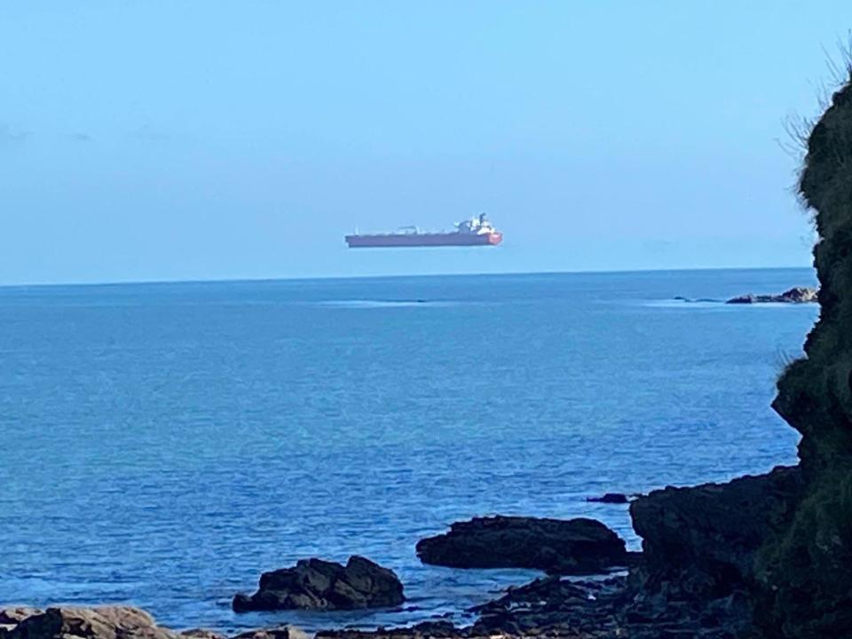 A tanker appears to float above the sea when viewed from the Cornwall coast (David Morris/APEX)