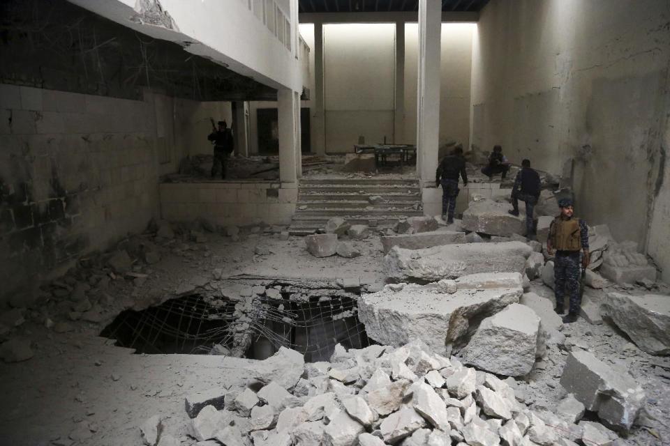 Iraqi federal police inspect the inside of Mosul's heavily damaged museum. Most of the artifacts inside the building appeared to be completely destroyed. The basement level that was the museum's library had been burned. The floors were covered in the ashes of ancient manuscripts, in western Mosul, Iraq, Wednesday, March 8, 2017. (AP Photo/Khalid Mohammed)