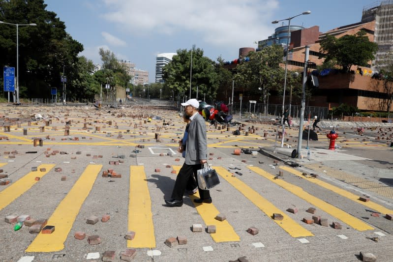 People cross a road scattered with bricks outside the Polytechnic University in Hong Kong