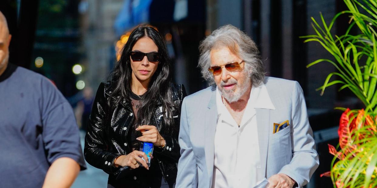 Al Pacino and Noor Alfallah walking on the sidewalk.