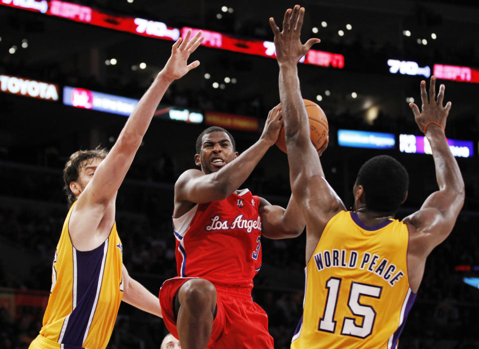 Los Angeles Clippers' Chris Paul, center, goes to the basket between Los Angeles Lakers' Pau Gasol, left, of Spain, and Metta World Peace, right, during the first half of an NBA preseason basketball game in Los Angeles on Monday, Dec. 19, 2010. (AP Photo/Danny Moloshok)