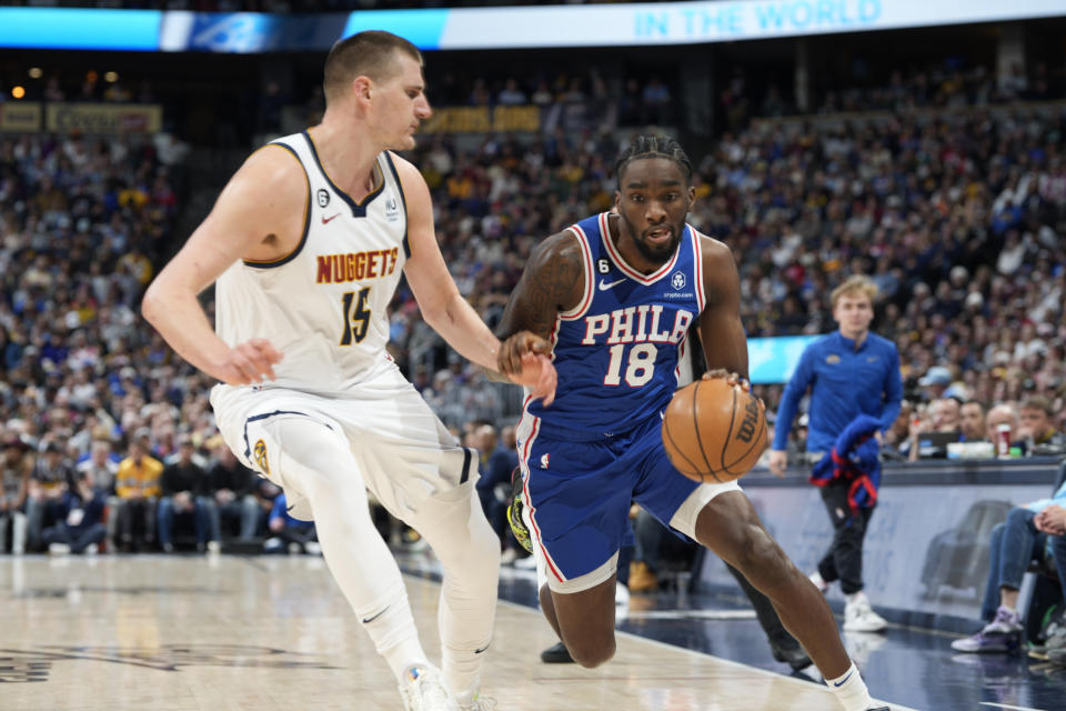 Philadelphia 76ers guard Shake Milton, right, drives to the rim as Denver Nuggets center Nikola Jokic defends in the first half of an NBA basketball game, Monday, March 27, 2023, in Denver. (AP Photo/David Zalubowski)