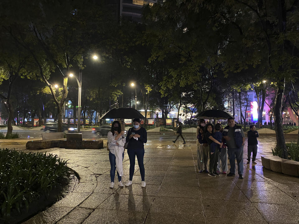 People stand under the rain after a strong earthquake on Reforma avenue in Mexico City, Tuesday, Sept. 7, 2021. The quake struck southern Mexico near the resort of Acapulco, causing buildings to rock and sway in Mexico City nearly 200 miles away. (AP Photo/Nelson Antoine)