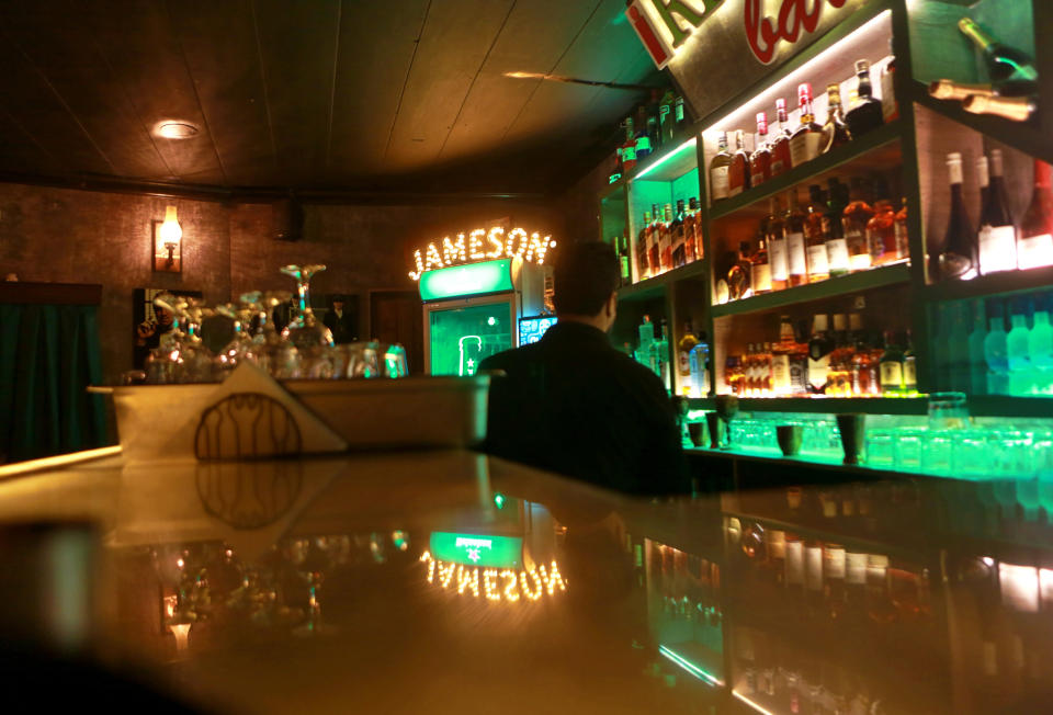 A waiter waits on customers at a cocktail bar hidden away in a dark corner of central Baghdad, Iraq, Wednesday, Jan. 27, 2021. Its owner, a Syrian migrant, opened the establishment a few weeks ago as a refuge for a hand-picked clientele that wants to evade the stigma of drinking alcohol in a conservative Muslim-majority society. But being a barman is a dangerous trade in Iraq, where alcohol shops are frequently targeted by disapproving militias. (AP Photo/Khalid Mohammed)