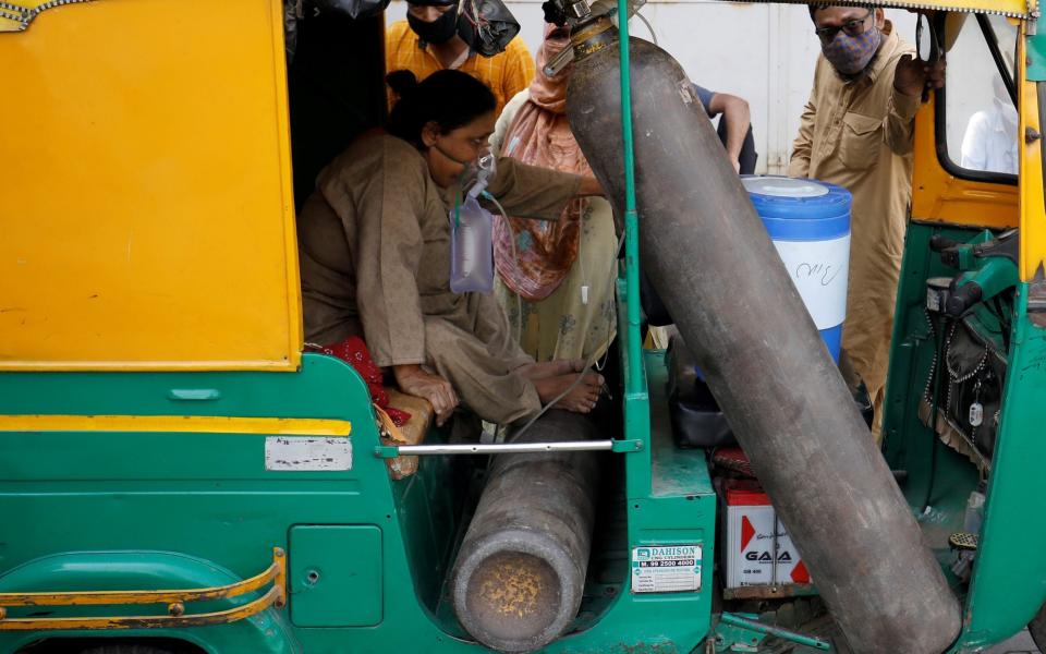 Aminbanu Memon wearing an oxygen mask sits in an autorickshaw waiting to enter a COVID-19 hospital for treatment