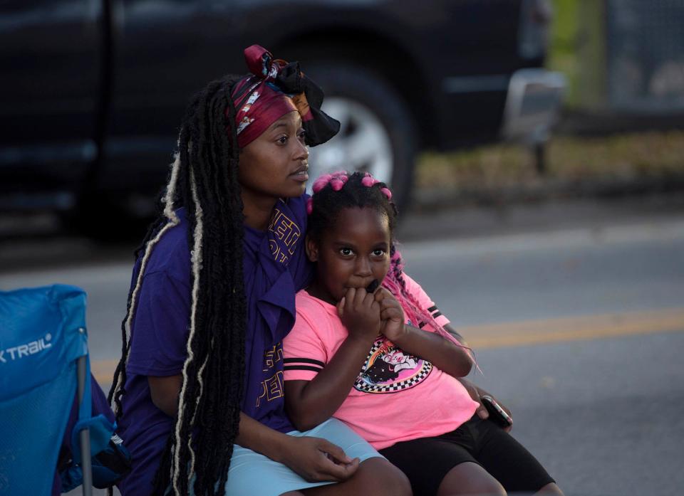 Tatiana Lewis hold her daughter Emara, 6, during the PUSH  to Curb Gun Violence block party Friday night on Tamarind Avenue in West Palm Beach.