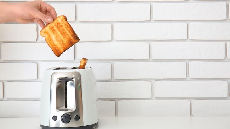 Hand grabbing toast from toaster