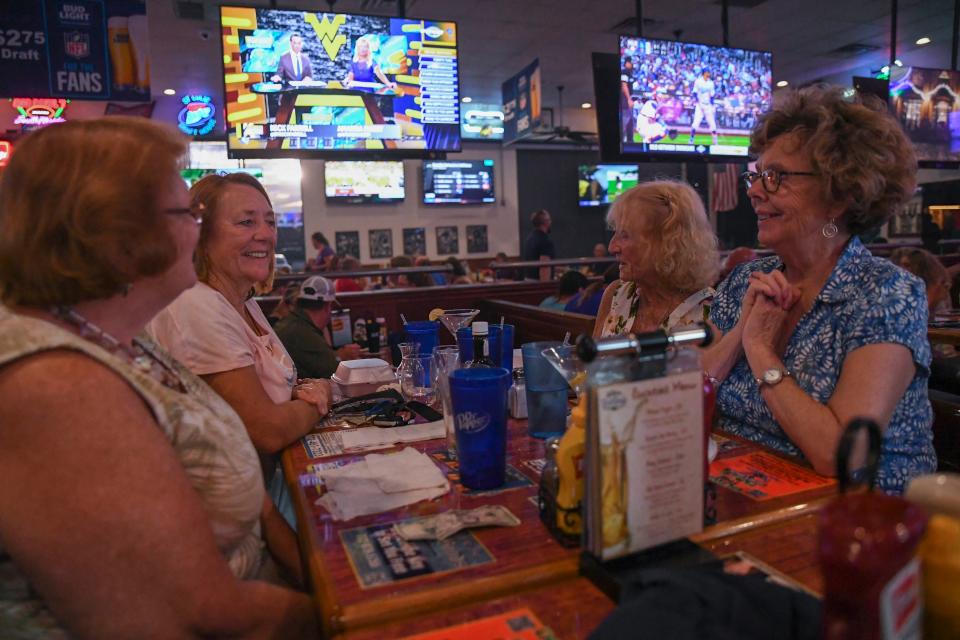 Surrounded by televisions featuring sports and news, Savanna Club residents (from left) Janell Howard, Kathleen Anson, Ginger Dunn, and Diane Fraser socialize after dinner on burger night at the St. Lucie Draft House on Wednesday, Aug,. 31, 2022, in Port St. Lucie. "We love coming here because we've never had a bad meal, the food is excellent, the service is excellent, and we love our lemon drop martinis," Fraser said.  