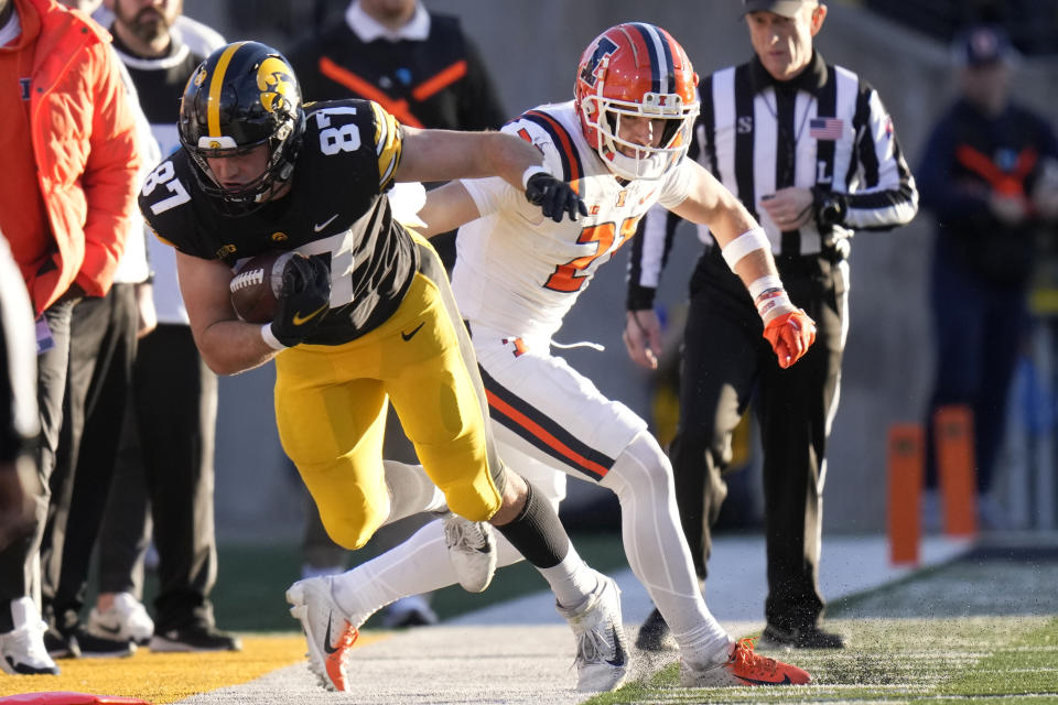 Iowa tight end Addison Ostrenga (87) is pushed out of bounds by Illinois defensive back Clayton Bush (21) after catching a pass during the first half of an NCAA college football game, Saturday, Nov. 18, 2023, in Iowa City, Iowa. (AP Photo/Charlie Neibergall)