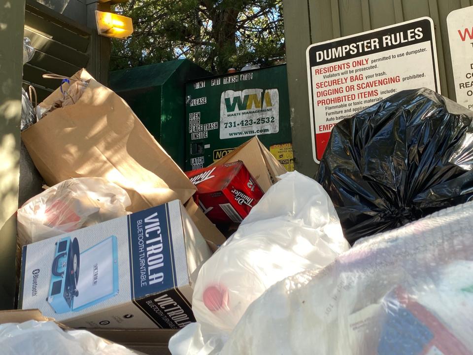 Trash spills out from a Waste Management dumpster.