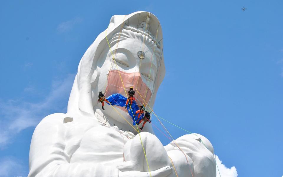 Workers place a mask on a 57 meters tall Buddhist goddess statue to pray for the end of the pandemic at Houkokuji Aizu Betsuin in Aizuwakamatsu, Fukushima Prefecture -  Houkokuji Aizu Betsuin