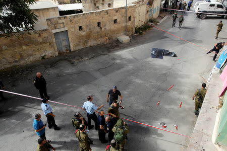 The dead body of a Palestinian is covered as Israeli forces gather at the scene of a stabbing attack in Hebron, in the occupied West Bank October 22, 2018. REUTERS/Mussa Qawasma