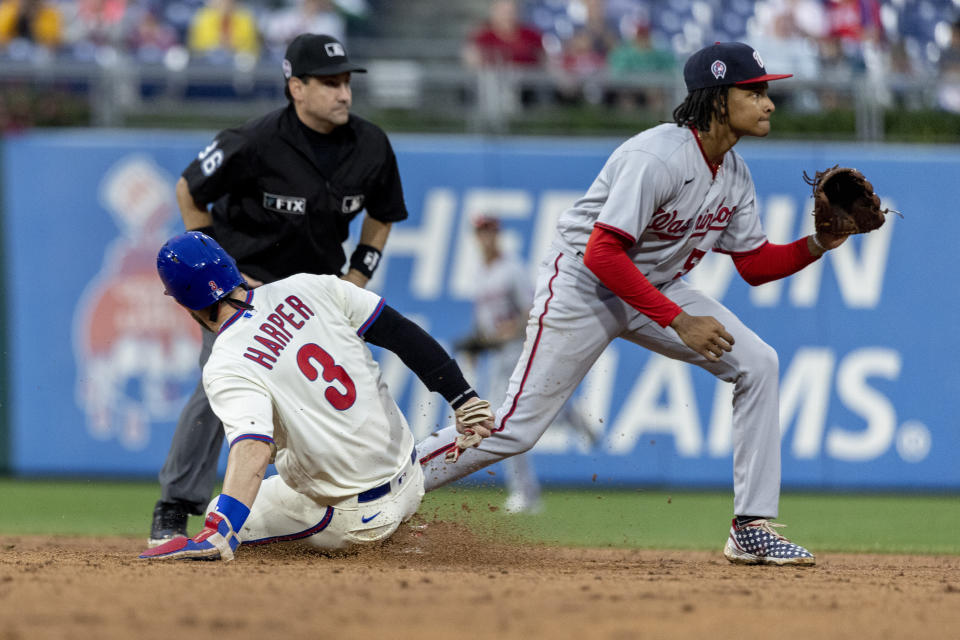 Philadelphia Phillies' Bryce Harper (3) is safe at second base on a single by J.T. Realmuto before Washington Nationals shortstop CJ Abrams (5) can make a catch during the fifth inning of a baseball game, Sunday, Sept. 11, 2022, in Philadelphia. (AP Photo/Laurence Kesterson)