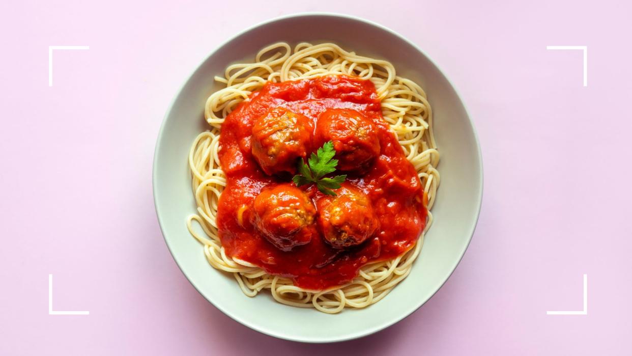  Bowl of spaghetti and meatballs on plain white china plate, representing the question of can menopause cause a loss of taste and smell. 