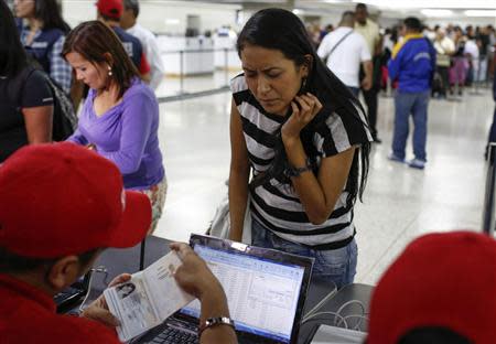 A passenger presents her documents at a special check point of the state currency board Cadivi in the Simon Bolivar airport in La Guaira, outside Caracas October 15, 2013. REUTERS/Carlos Garcia Rawlins