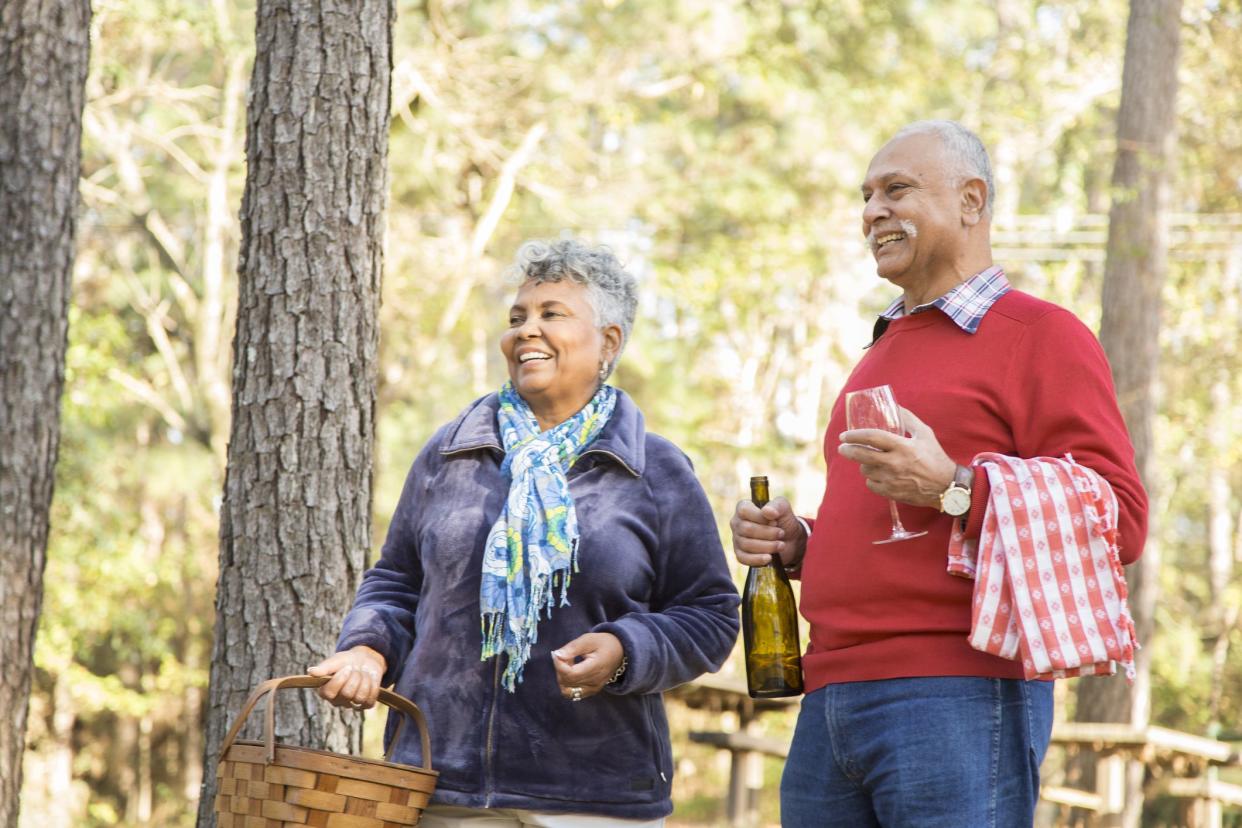 Active senior adult couple have a picnic in wooded park area.