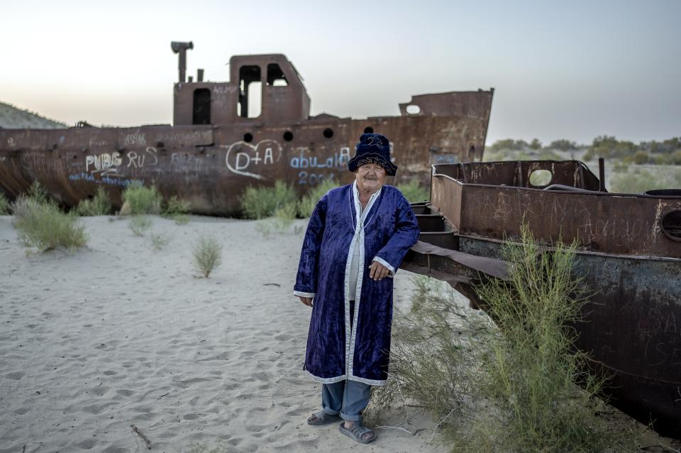 Soleyman poses for a photo in front of an old boat in the area where the Aral Sea once was in Muynak, Uzbekistan, Thursday, July 13, 2023. (AP Photo/Ebrahim Noroozi)