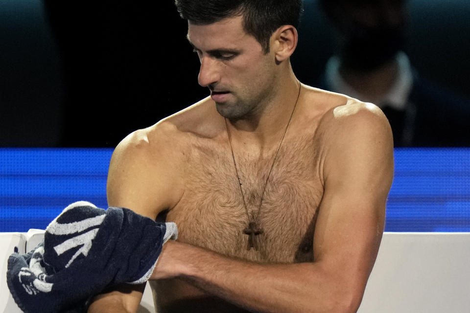 Novak Djokovic of Serbia wipes his body during his ATP World Tour Finals, singles semifinal, tennis match with Alexander Zverev of Germany, at the Pala Alpitour in Turin, Italy, Saturday, Nov. 20, 2021. (AP Photo/Luca Bruno)