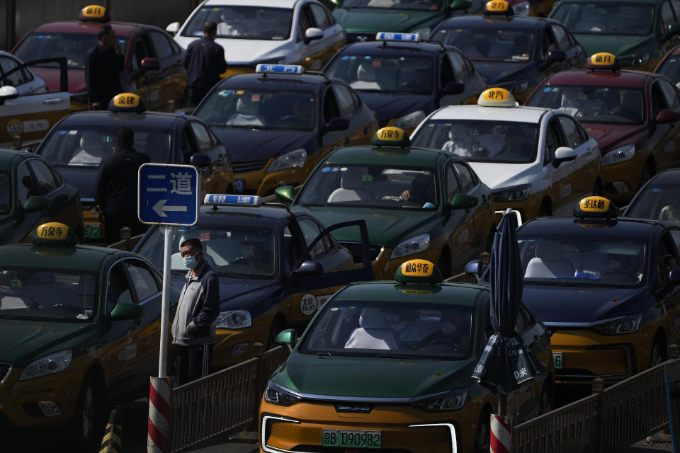 A taxi driver wearing a face mask stands watch as they pile up to wait for customers at a train station in Beijing, Thursday, Oct. 6, 2022. Sprawling Xinjiang is the latest Chinese region to be hit with sweeping COVID-19 travel restrictions, as China further ratchets up control measures ahead of a key Communist Party congress later this month. (AP Photo/Andy Wong)