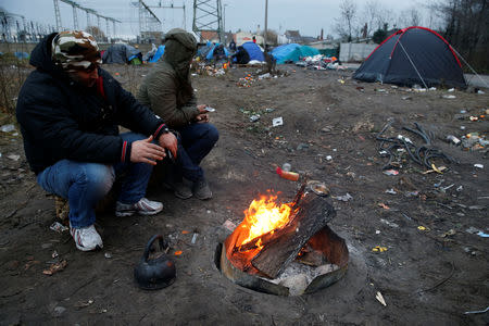 Iranian Kurdish migrants warm their hands by a fire in a shelter's camp in Calais, France, January 12, 2019. Picture taken January 12, 2019. REUTERS/Pascal Rossignol
