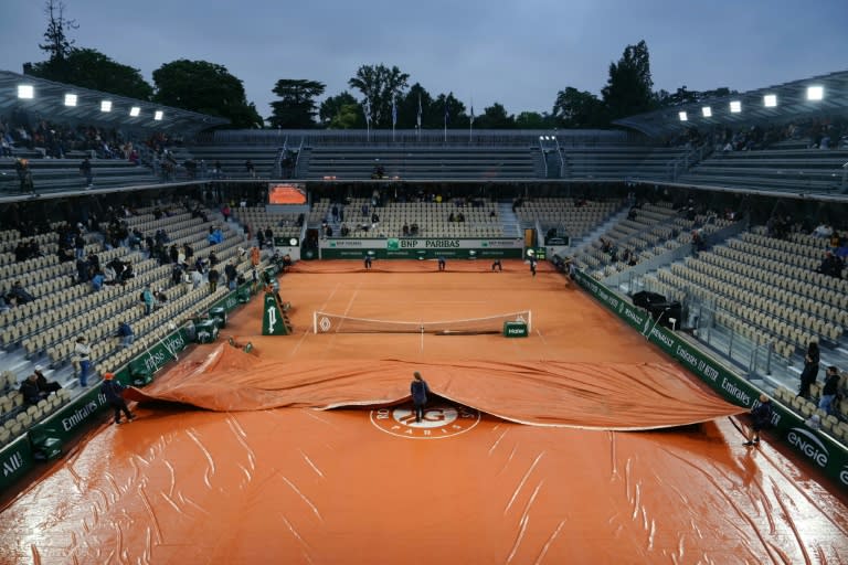 Rain pain: Staff members remove the tarpaulin on Court Simonne Mathieu, after the rain, on day seven (Dimitar DILKOFF)