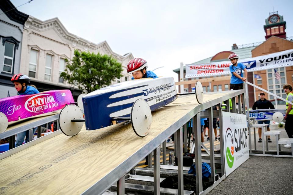 Racers Thea Denovich, 7, left, and Payton Gingrich, 9, right, leave the starting ramp during the St. Johns Soap Box Derby on Sunday, June 11, 2023, in downtown St. Johns.