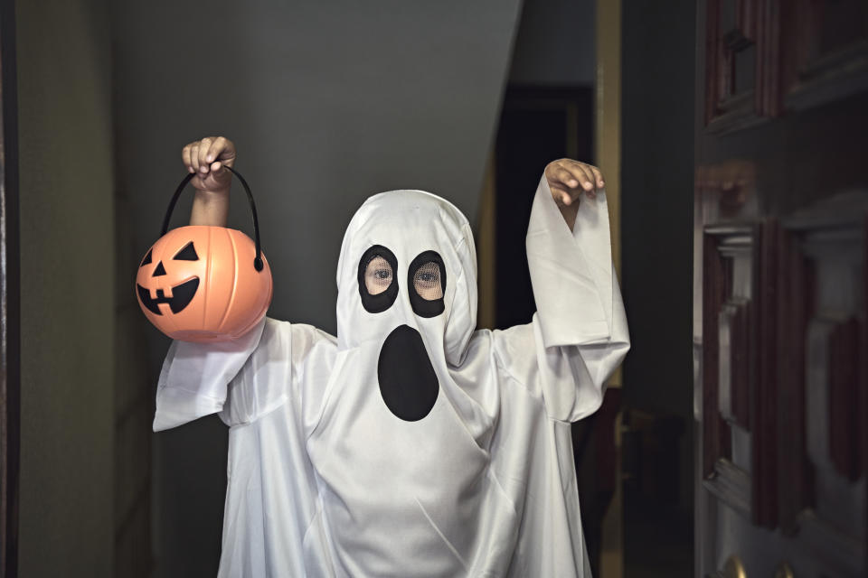 They knock on the door and when it opens, a boy dressed as a ghost appears in the foreground.  Trick or Treat!