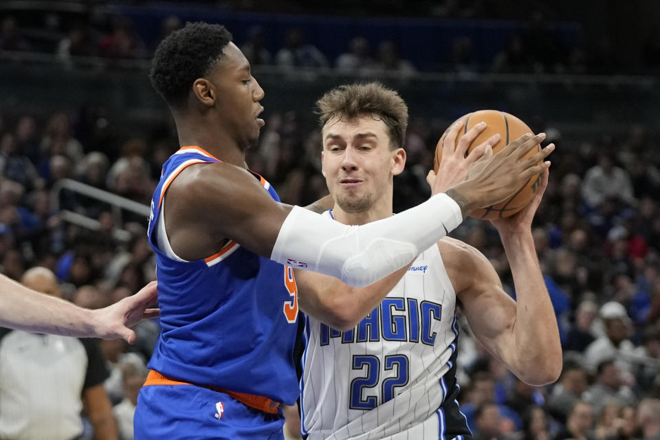 New York Knicks guard RJ Barrett, left, stops Orlando Magic forward Franz Wagner (22) who tries to get to the basket during the second half of an NBA basketball game, Friday, Dec. 29, 2023, in Orlando, Fla. (AP Photo/John Raoux)