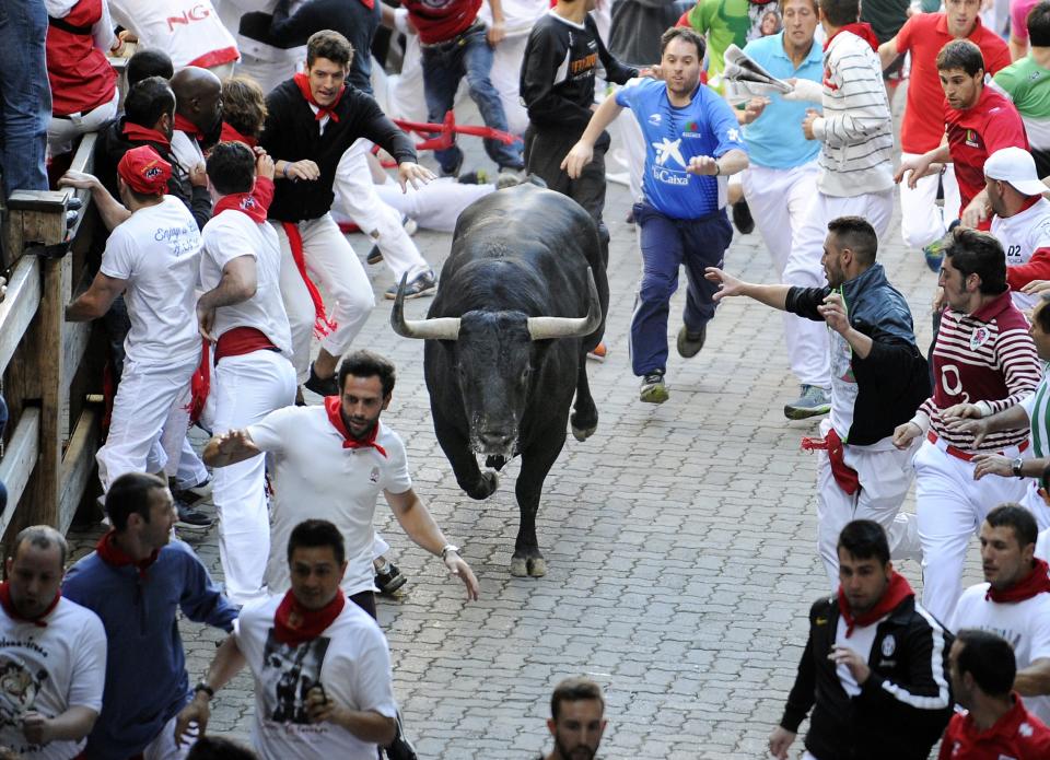 Participants run in front of Victoriano del Rio Cortes' bulls during the third 'encierro' (bull-run) of the San Fermin Festival in Pamplona, northern Spain, on July 9, 2015. The festival is a symbol of Spanish culture that attracts thousands of tourists to watch the bull runs despite heavy condemnation from animal rights groups. AFP PHOTO/ ANDER GILLENEA        (Photo credit should read ANDER GILLENEA/AFP/Getty Images)