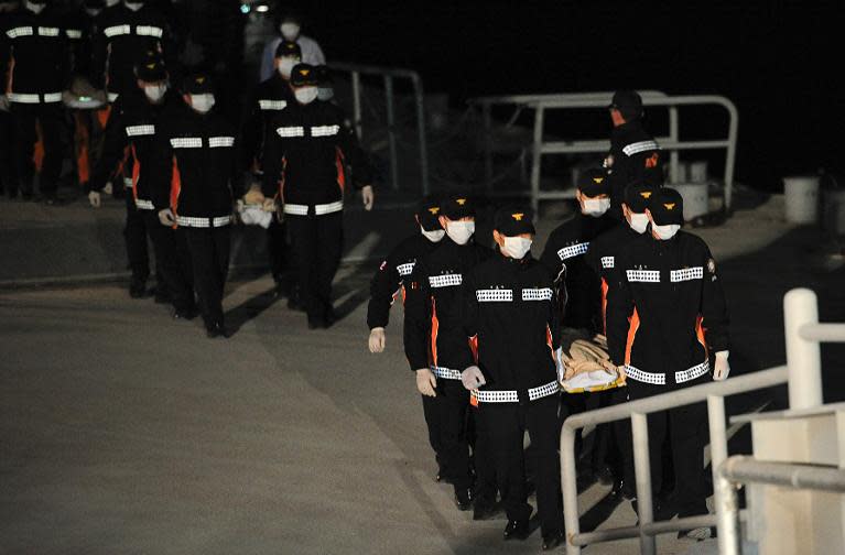 Members of South Korean rescue team carry the bodies of a passenger retrieved from a capsized ferry at a harbour in Jindo on April 19, 2014