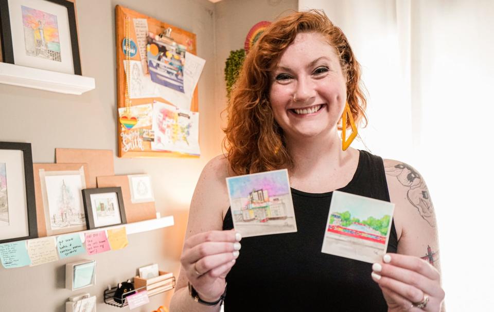 Artist Skye Lee Smith, who attended Herron School of Art + Design in Indianapolis, holds two of her architectural watercolor paintings, Thursday, July 28, 2022, at her Indianapolis home. Smith, who paints Indiana landmarks, also takes commissions to paint private homes. Here she holds paintings of The Vogue Theater and the rainbow bridge in Broad Ripple Village.