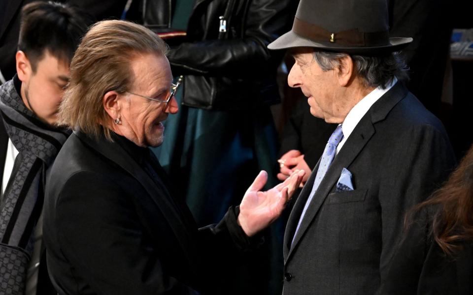 Irish singer-songwriter Bono chats with Paul Pelosi, still wearing a hat after his assault - SAUL LOEB/AFP