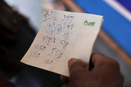 A man holds a paper with numbers, before buying lottery tickets at Wat Kunnatri Ruttharam temple in Bangkok, Thailand November 1, 2018. Picture taken November 1, 2018. REUTERS/Jorge Silva