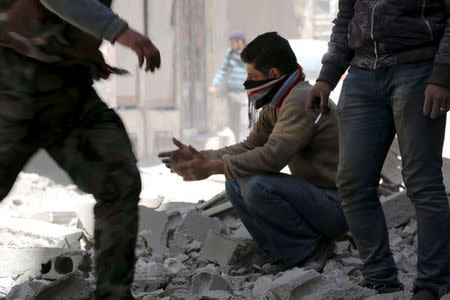 Residents stand upon the rubble of collapsed buildings after what activists said was shelling by forces loyal to Syria's President Bashar Al-Assad at Ain Tarma in eastern Ghouta, a suburb of Damascus, Syria April 26, 2015. REUTERS/Amer Almohibany