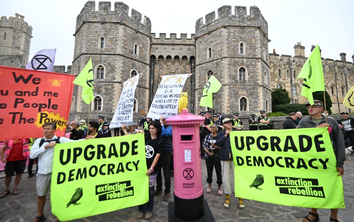 Protesters outside Windsor Castle on Saturday with a pink postbox filled with handwritten messages urging the King to 'intervene in the worsening climate crisis'