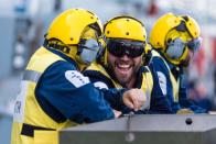 <p>An aircraft handler smiles on the fligth deck (Si Ethell/MoD) </p>