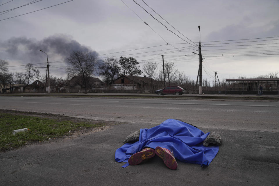 FILE - A body lies covered by a tarp in the street in Mariupol, Ukraine, March 7, 2022. (AP Photo/Evgeniy Maloletka, File)