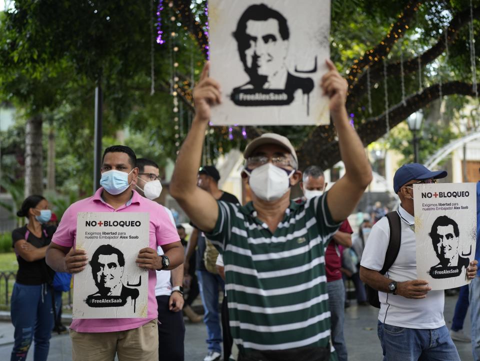 People hold signs with the image of businessman Alex Saab who has been extradited to the U.S., during a demonstration demanding his release, in Caracas, Venezuela, Sunday, Oct. 17, 2021. Saab, a close ally of Venezuela's President Nicolas Maduro, who prosecutors in the U.S. believe could be the most significant witness ever about corruption in the South American country, was extradited from Cabo Verde and is now in U.S. custody. (AP Photo/Ariana Cubillos)