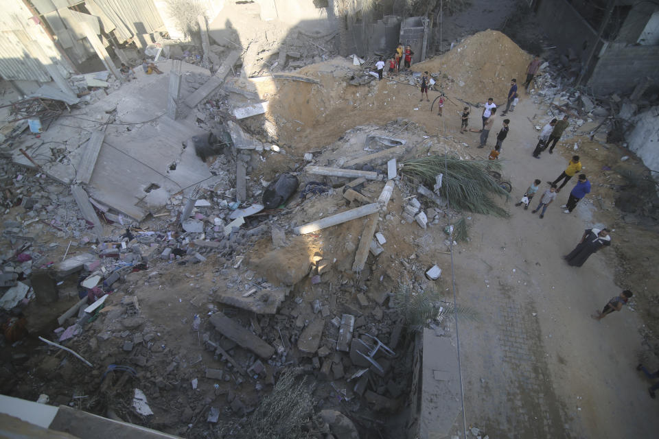 Palestinians stand by the building of the Zanon family, destroyed in Israeli airstrikes in Rafah, Gaza Strip, Saturday, Oct. 14, 2023. (AP Photo/Hatem Ali)