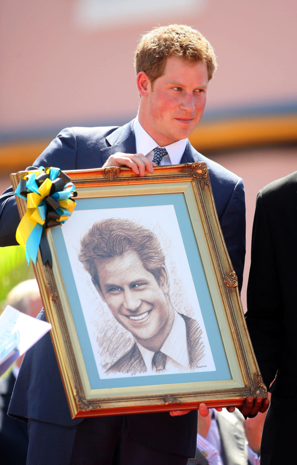 Britain's Prince Harry shows a portrait depicting him after received it as a present in Nassau, Bahamas, Sunday, March 4, 2012. The Prince visited the Bahamas as part of a Diamond Jubilee tour that includes visits to Belize, the Bahamas, Jamaica and Brazil as a representative of Queen Elizabeth II.  (AP Photo/Felipe Major)