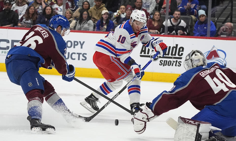 New York Rangers left wing Artemi Panarin, center, shoots the puck past Colorado Avalanche defenseman Sean Walker on goaltender Alexandar Georgiev during the second period of an NHL hockey game Thursday, March 28, 2024, in Denver. (AP Photo/David Zalubowski)