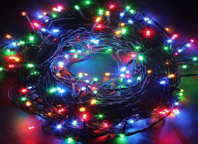 An illuminated string of LED mini Christmas tree lights in a dark room.