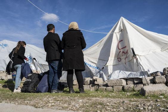 A couple who recently fled conscription in northern Syria stand outside the tent assigned to them (Bel Trew)