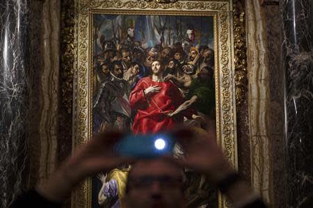 A man takes a picture underneath El Greco's "El Expolio", or "The Disrobing of Christ", painting during a ceremony marking its return following restoration to the sacristy of the Cathedral of Toledo January 22, 2014. REUTERS/Paul Hanna