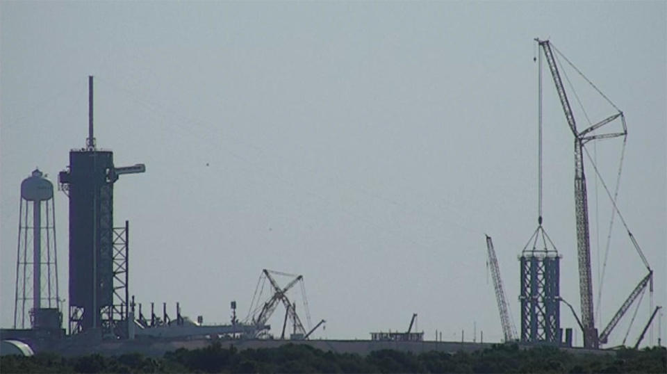 The second gantry segment was lifted and lowered into place early Thursday (right), about 1,000 feet from the company's Falcon 9 pad and gantry (left). / Credit: CBS News