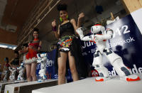 Models dance with the humanoid robot "NAO" during a news conference in Bangkok June 19, 2012. NAO, the newest humanoid technology from Europe, was brought in to promote "Thailand's Manufacturing Expo 2012" which will be held from June 21-24 in Bangkok. REUTERS/Chaiwat Subprasom (THAILAND - Tags: SCIENCE TECHNOLOGY BUSINESS)