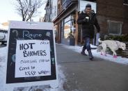 A man walks his dog past a spa advertising free hot showers for residents whose electricity remains knocked out by an ice storm, on Danforth Avenue in Toronto December 24, 2013. REUTERS/Chris Helgren (CANADA - Tags: ANIMALS ENERGY ENVIRONMENT)